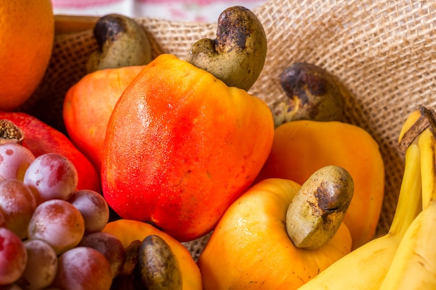 Frutta in cestino di legno: anacardi, arance, uva, banana, mango e papaia