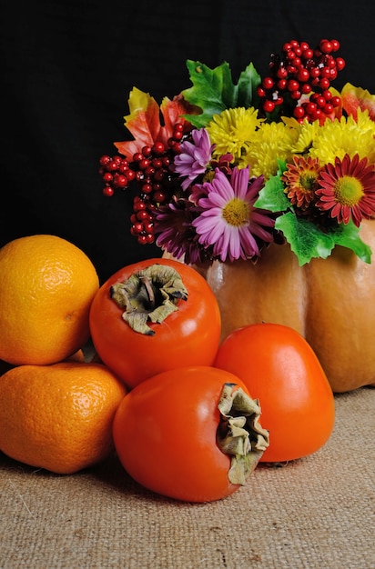 Frutta in tavola con fiori in vaso zucca