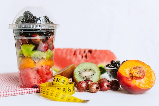 Frutta in un bicchiere, un nastro per misurare il corpo. Concetto di alimentazione sana e perdita di peso