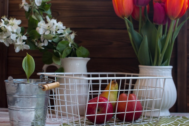 Frutta in un cesto di vimini su uno sfondo di legno con fiori in un vaso Il concetto di un villaggio Ecologia pulita