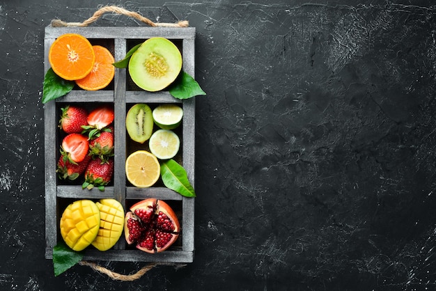 Frutta in una scatola di legno Agrumi melone melograno fragola banana Vista dall'alto Spazio libero per il testo