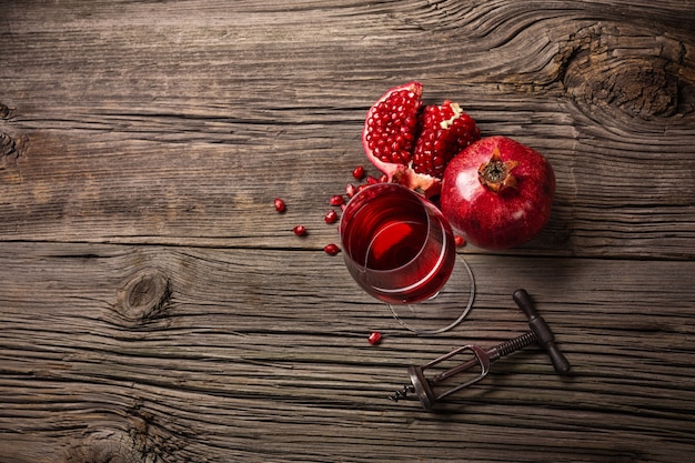 Frutta matura del melograno con un bicchiere di vino e una cavaturaccioli su un fondo di legno