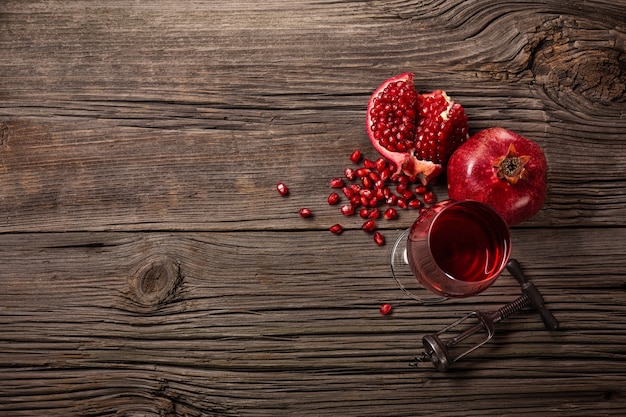 Frutta matura del melograno con un bicchiere di vino e una cavaturaccioli su un fondo di legno