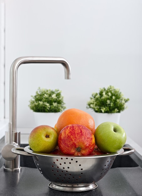 Frutta nella tazza sul lavello della cucina vicino al rubinetto dell'acqua.