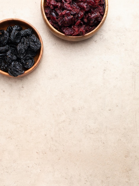 Frutta secca sana prugne di mirtillo rosso in una ciotola di legno vista dall'alto flatlay