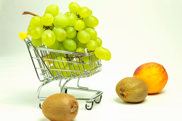 Frutta su uno sfondo bianco e posto per il testo Frutta in un cesto grappoli d'uva maturi e pesche con kiwi e sfondo bianco