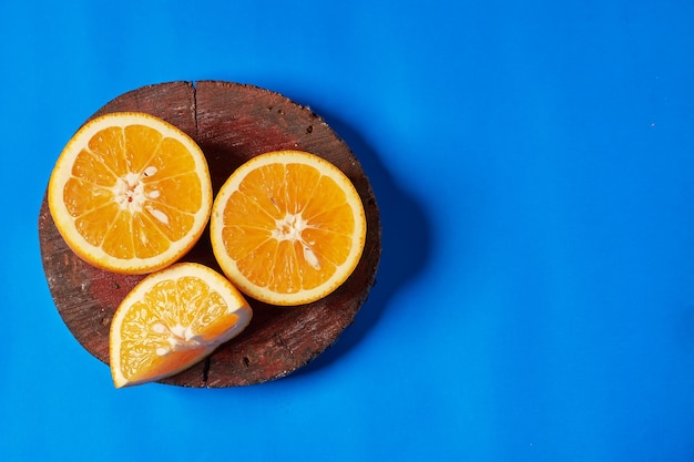 Frutta succosa arancione sul piatto di legno e sullo sfondo blu. Frutta biologica e fresca.