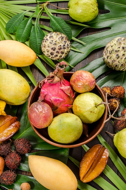 Frutta tropicale tailandese assortita su un fondo rustico di legno scuro.