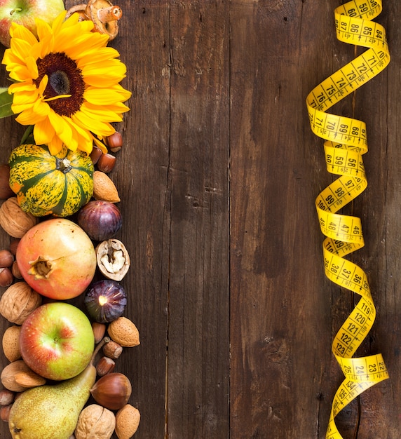 Frutta, verdura e fiori di autunno con nastro adesivo di misurazione sulla vista di legno del piano d'appoggio con lo spazio della copia