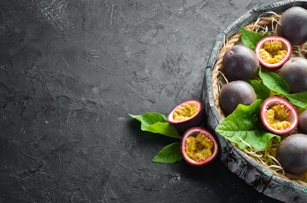 Frutti della passione con foglie su sfondo nero Frutti tropicali Vista dall'alto Spazio libero per il testo