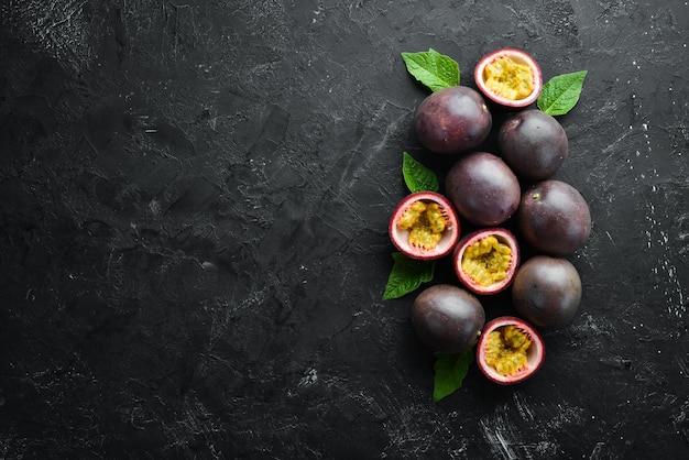 Frutti della passione con foglie su sfondo nero Frutti tropicali Vista dall'alto Spazio libero per il testo