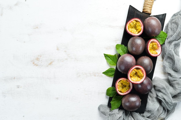 Frutti della passione con una foglia su uno sfondo di legno bianco Frutti tropicali Vista dall'alto Spazio libero per il testo