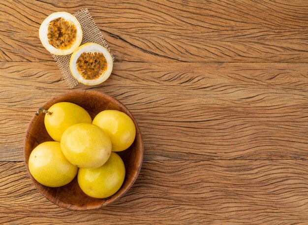 Frutti della passione in una ciotola con frutta tagliata su un tavolo di legno con spazio per la copia