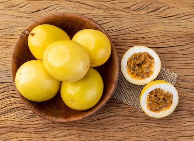 Frutti della passione in una ciotola con frutta tagliata su un tavolo di legno