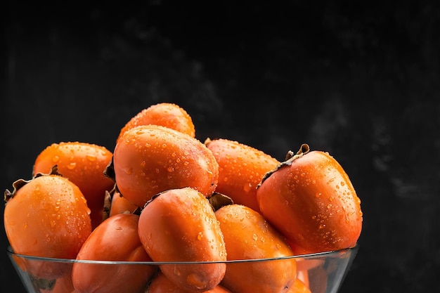 Frutti di cachi con gocce d'acqua su sfondo nero