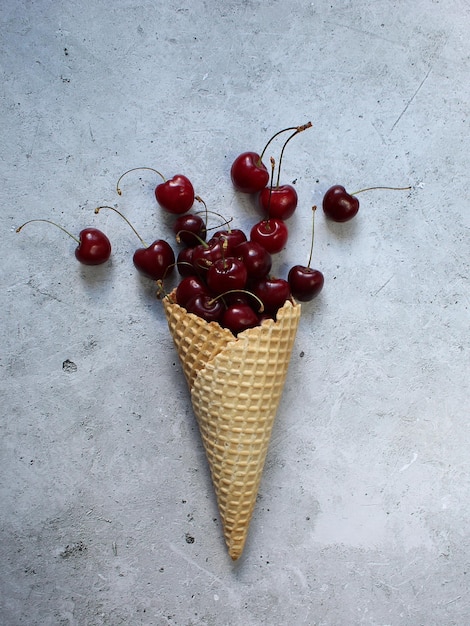 Frutti di ciliegia in un cono gelato Posa piatta Concetto estivo minimo