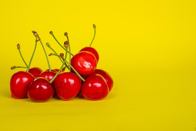 Frutti di ciliegia isolati su sfondo giallo. Primo piano di ciliegie con spazio per il testo.