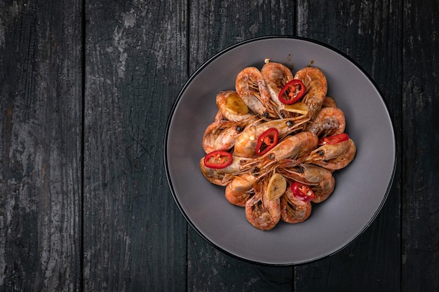 frutti di mare alla griglia in un piatto rotondo grigio su un tavolo di legno scuro