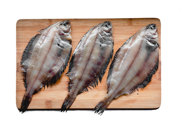 Frutti di mare crudi del pesce della passera su un tagliere di legno isolato su fondo bianco Mangiare sano