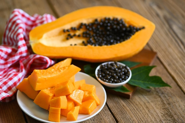 Frutti di papaia su sfondo di legno fetta di papaia matura fresca su piastra bianca frutta tropicale con semi di papaia e foglie di foglie di papaia