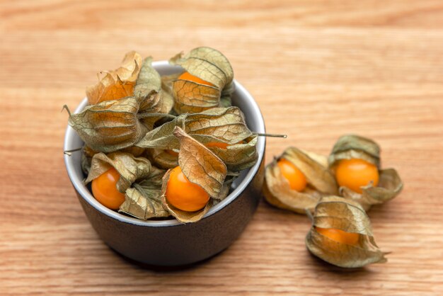 Frutti di Physalis su un tavolo di legno. Bacche di physalis gialle dolci in una tazza su fondo di legno.