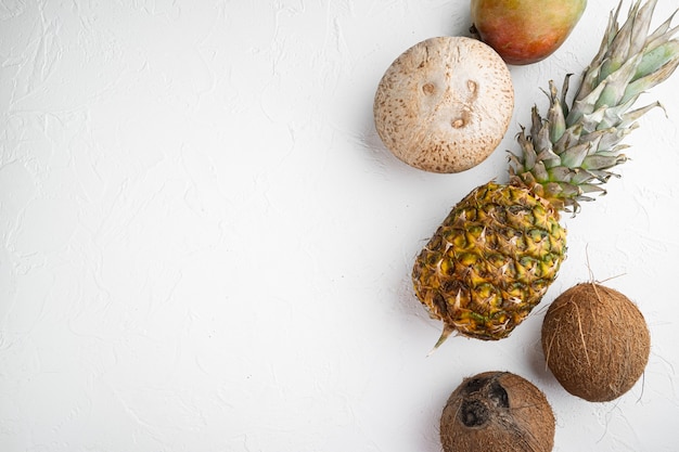 Frutti esotici, ananas e set di cocco, su sfondo di tavolo in pietra bianca, vista dall'alto piatta, con spazio di copia per il testo