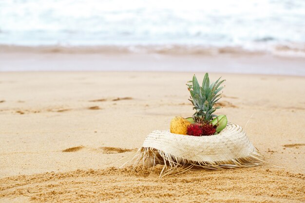 Frutti esotici in un cappello di paglia in spiaggia