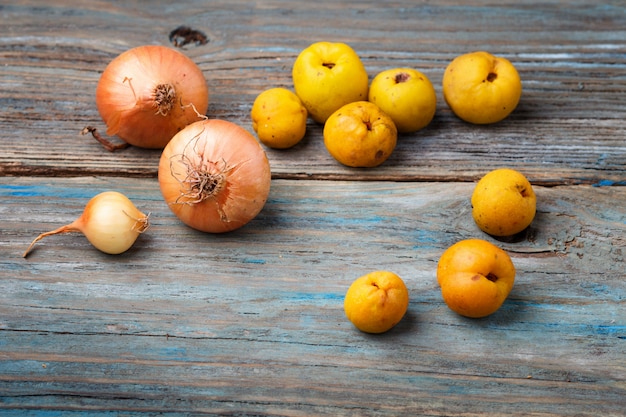 Frutti gialli e cipolle su un legno blu