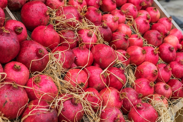 Frutti maturi del melograno con gocce d'acqua sul bancone con paglia.