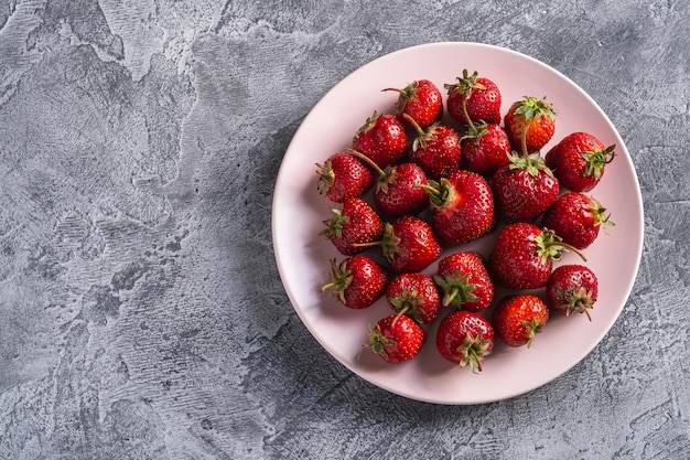 Frutti maturi freschi della fragola in piatto rosa