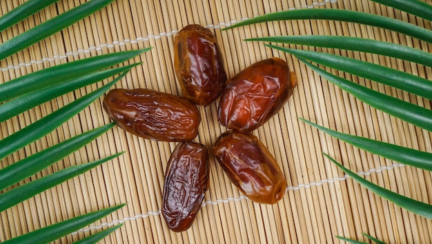 Frutti secchi di palma da datteri o kurma su sfondo di bambù Tradizionale ramadan delizioso e salutare