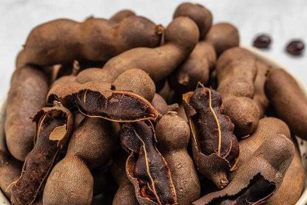 Frutti tropicali Fagioli di Tamarindo in guscio su un blocco di macellai marrone su uno sfondo scuro menu banner di frutta sana ricetta posto per testo vista dall'alto