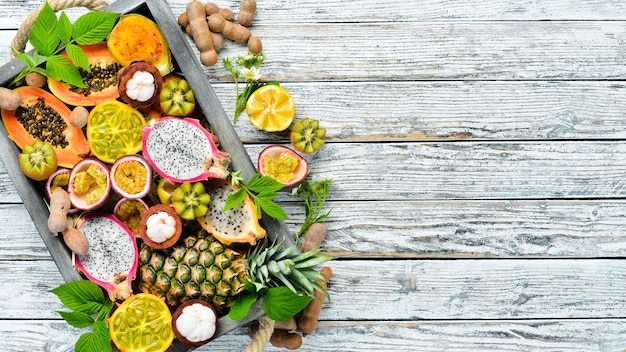 Frutti tropicali su fondo bianco: papaia, mangostano, frutti di cactus, pytahaya, ananas. Vista dall'alto. Spazio libero per il testo.