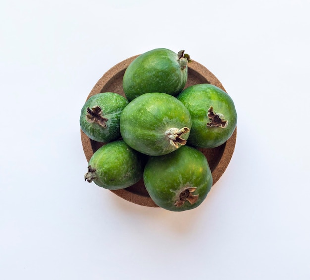 Frutti verdi di feijoa in un piatto di sughero isolato su uno sfondo bianco