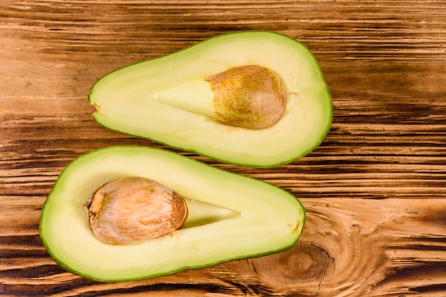 Frutto di avocado diviso in due su tavola in legno rustico. Vista dall'alto