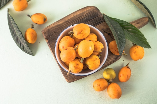 Frutto di nespolo maturo Eriobotrya japonica e foglie di nespola verde su tavola di legno Vista dall'alto