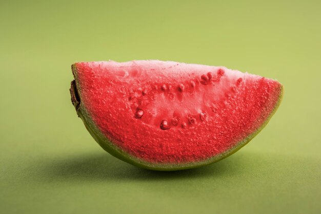 Frutto rosso fresco Guava noto anche come Amrood in Hindi e Perù in Marathi, servito in un cesto intero o fette su sfondo colorato. Messa a fuoco selettiva