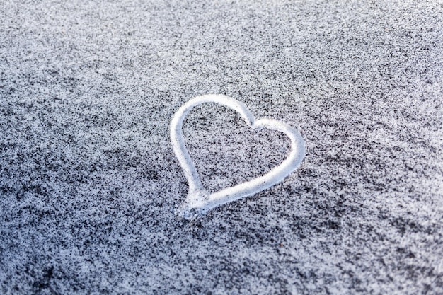 Fuliggine nera dal locale caldaia su neve bianca Un cuore è dipinto sulla neve povera ecologia