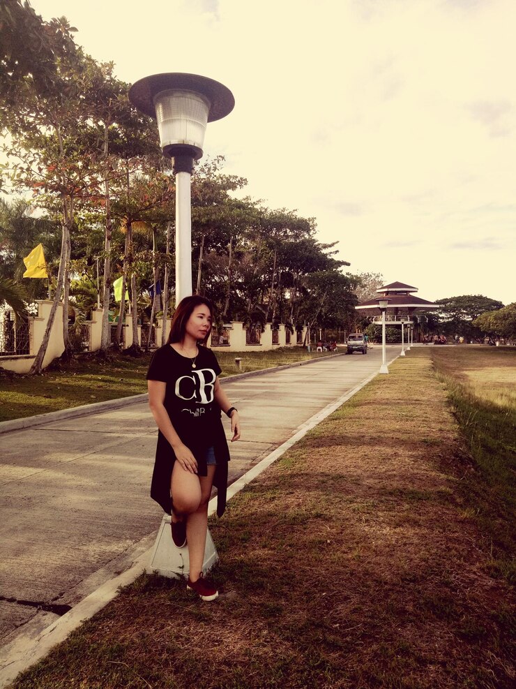 Photo full length of young woman leaning on street light at park