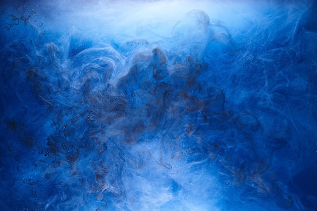 Fumo blu su sfondo di inchiostro nero, nebbia colorata, mare oceanico vorticoso astratto, pigmento di vernice acrilica sott'acqua