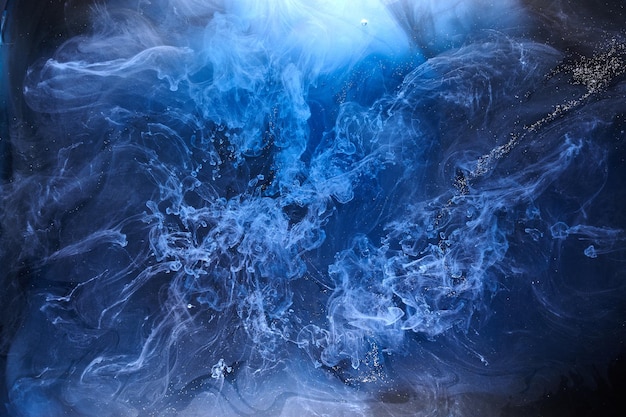 Fumo blu su sfondo di inchiostro nero, nebbia colorata, mare oceanico vorticoso astratto, pigmento di vernice acrilica sott'acqua