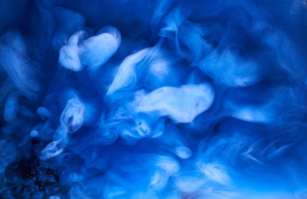 Fumo blu su sfondo di inchiostro nero, nebbia colorata, mare oceano vorticoso astratto, pigmento di vernice acrilica sott'acqua