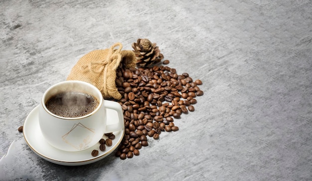 Fumosi chicchi di caffè tazza di caffè e borsa su sfondo bianco astratto