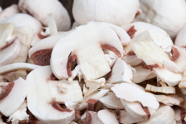 Funghi champignon affettati durante la cottura, primo piano di funghi tagliati per il trattamento termico