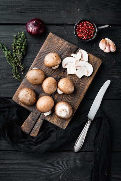 Funghi champignon marroni insieme, sulla tavola di legno nera