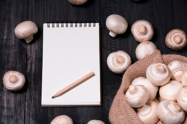 funghi champignon sul tavolo nero di legno e taccuino di scrittura