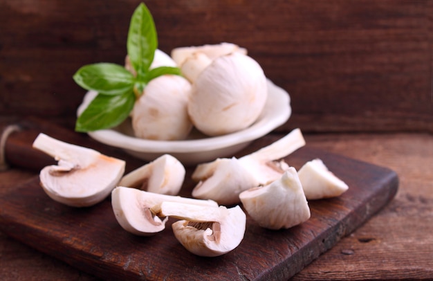 Funghi champignon tagliati a fette sulla vecchia tavola di legno