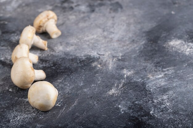 Funghi crudi bianchi deliziosi posti sulla superficie di marmo.