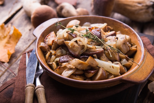 Funghi di bosco fritti, porcini, cipolle. Piatto rustico in una padella, alimento vegetariano di autunno in cima alla vista