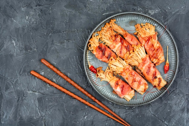 Funghi Enoki o enokitake arrostiti in pancetta su piatto Funghi avvolti in pancetta Flat lay con spazio per copiare